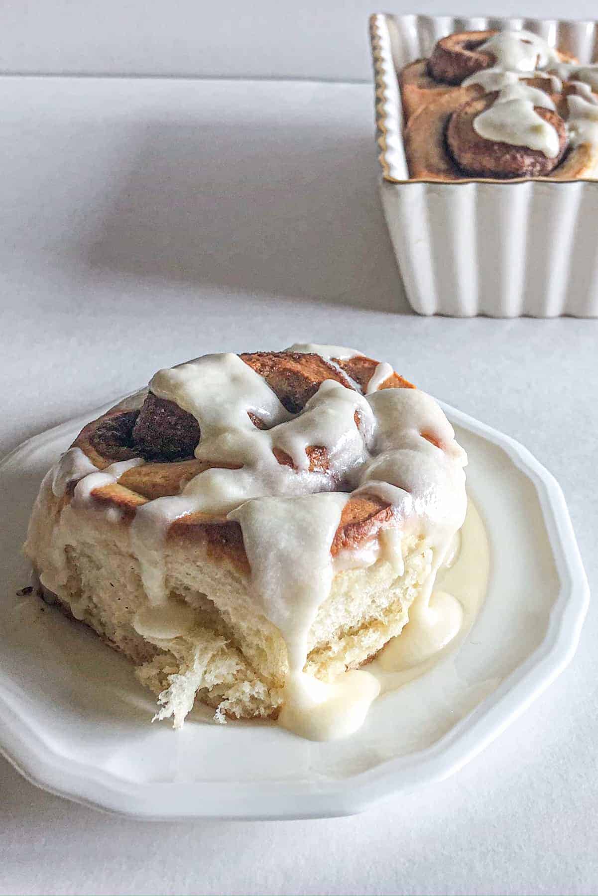 cinnamon roll on a plate with icing on top.