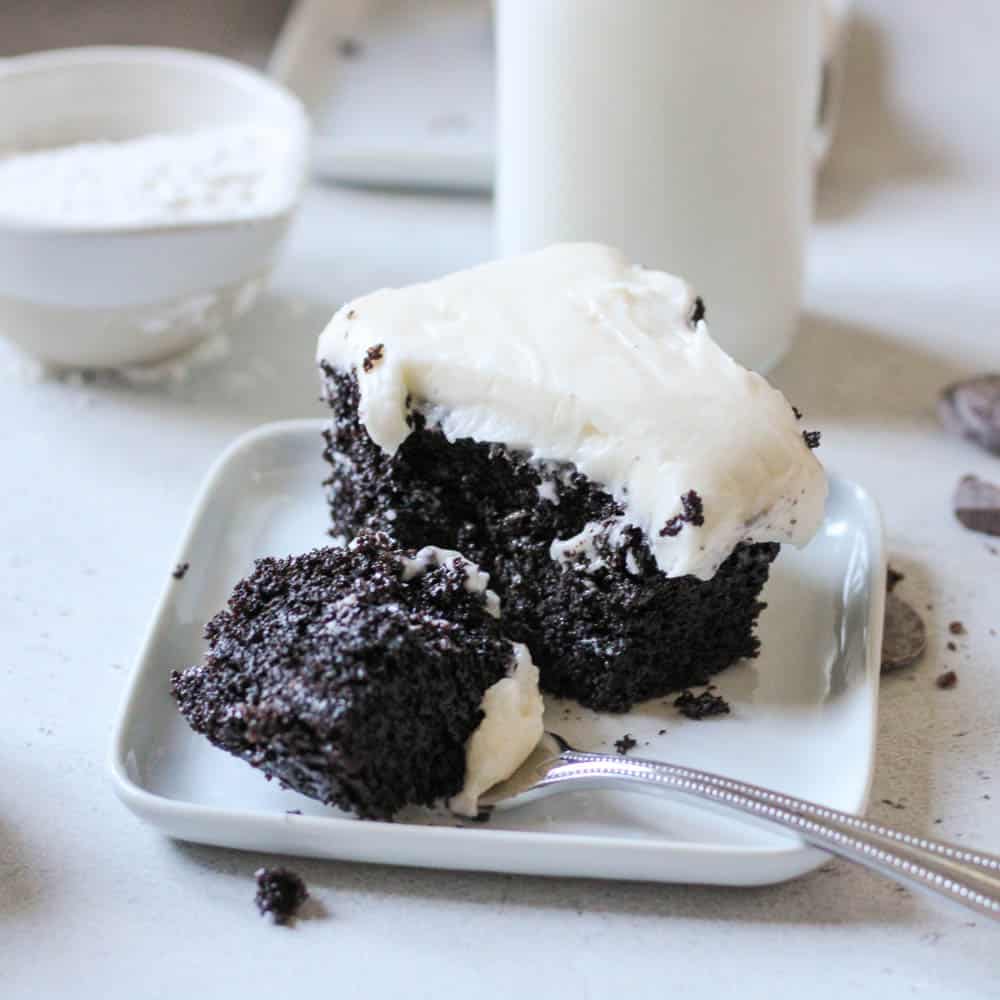 a bite of chocolate cake with vanilla frosting on a fork